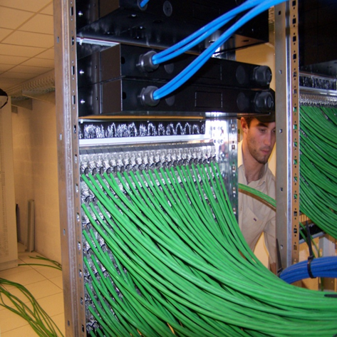 Technicien spécialisé en train de câbler un répartiteur informatique